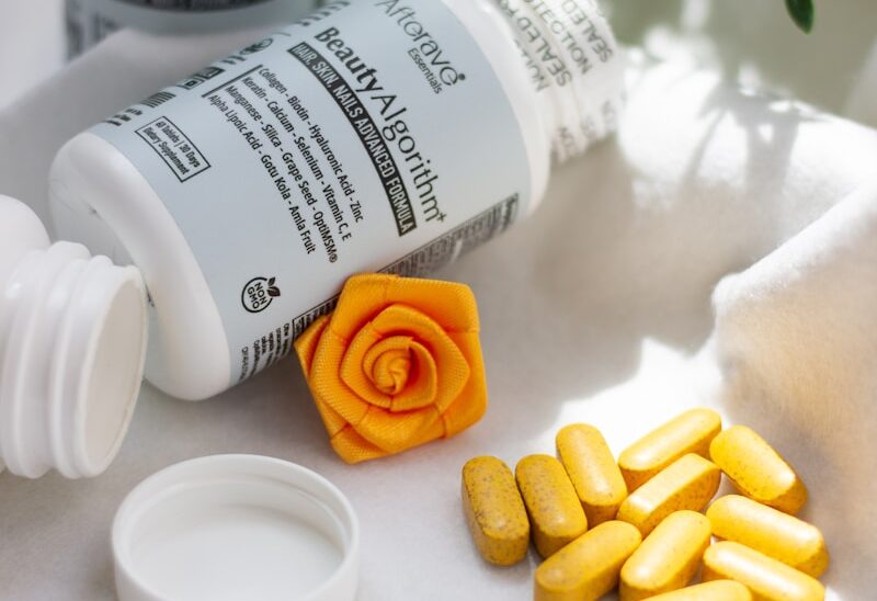 A close up of a bottle of pills next to a flower